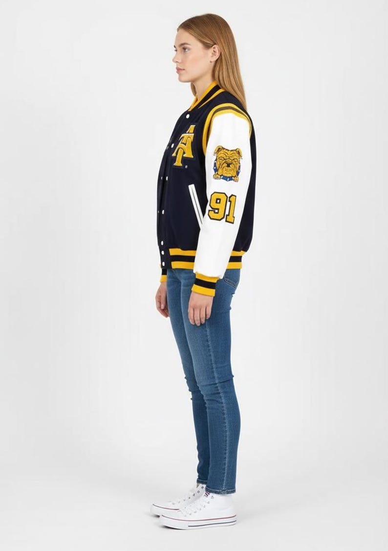 May include: Navy blue and white varsity jacket with yellow accents. Features a bulldog patch and the number 91 on the sleeve. The jacket has a button-up front and is worn with blue jeans and white sneakers.