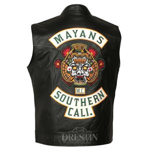 Op de afbeelding: Zwart leren vest met een "Mayans M.C. Southern Cali" patch op de rug. De patch heeft een gedetailleerd tribaal ontwerp in rood, groen, oranje en wit. Het vest heeft een klassieke biker stijl.