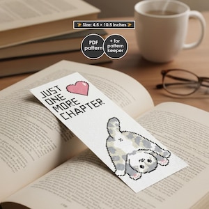 May include: A white bookmark with a cross-stitch design featuring a gray and white cat and the text "JUST ONE MORE CHAPTER" with a pink heart. The bookmark measures 4.5 x 10.5 inches.