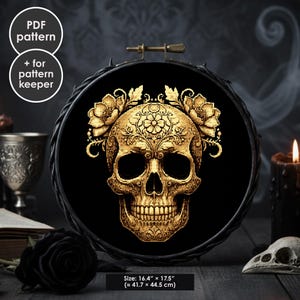 May include: A cross-stitch pattern featuring a golden skull with floral details, set against a black backdrop within a black embroidery hoop. The text "PDF pattern" and "+ for pattern keeper" are in white circles. The size is 41.7 x 44.5 cm.