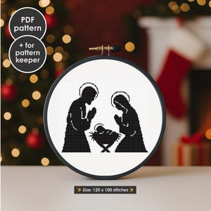 May include: A black and white cross-stitch pattern of the Nativity scene, framed in a round hoop. The image shows Mary, Joseph, and baby Jesus. The text "PDF pattern + for pattern keeper" is in the upper left. The size is 120 x 100 stitches.