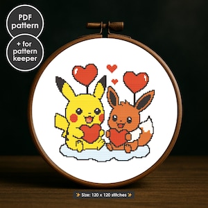 Puede incluir: Un bastidor de bordado de punto de cruz con Pikachu y Eevee sosteniendo corazones rojos, con globos en forma de corazón. El diseño está sobre un fondo blanco, enmarcado en un aro de madera. El texto en la imagen dice "PDF pattern" y "+ for pattern keeper". El tamaño es de 120 x 120 puntadas.