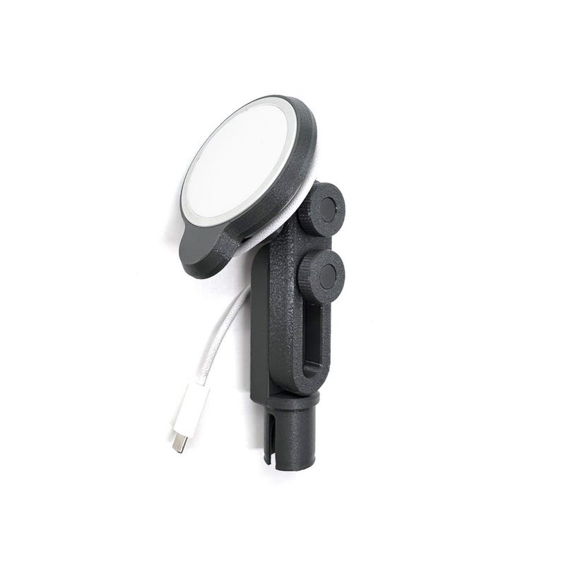May include: A black and gray phone charger mount with a white charging surface. The mount has a cylindrical base and adjustable knobs. A white charging cable is connected to the charger.