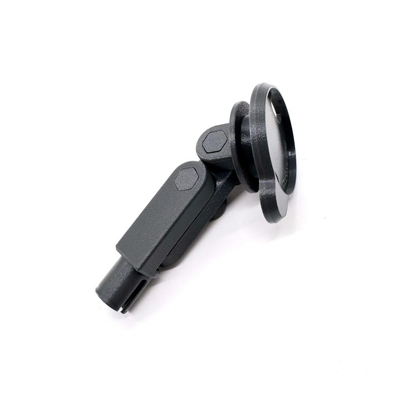 May include: A dark gray, adjustable device with a circular head and a segmented arm. The head has a raised, circular rim. The arm has two hexagonal joints. The base has a slotted end. The device is set against a white background.