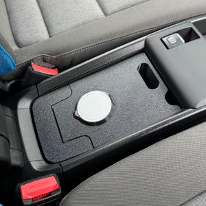 May include: A white ceramic mug with a black handle and the text "But First, Coffee" in a black, handwritten-style font. The mug is on a white surface.