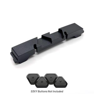 May include: Black, textured, rectangular device with a series of geometric cutouts. Below are four black, triangular buttons with white lettering. The text "S3XY Buttons Not Included" is below the buttons.