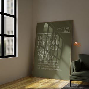 May include: A framed olive green poster with the text "TRUST IN THE LORD WITH ALL YOUR HEART" and "PROVERBS 3:5-6". The poster is displayed in a room with a window and a green armchair.