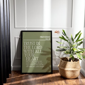 May include: A framed print with the text "TRUST IN THE LORD WITH ALL YOUR HEART" from Proverbs 3:5-6. The print has a green background and is displayed on a wooden floor next to a woven basket with a plant.