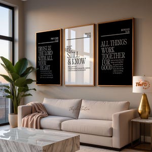 Op de afbeelding: Drie rechthoekige wandkunstwerken in dunne gouden lijsten. De linker- en rechterlijsten hebben zwarte achtergronden met witte tekst, terwijl de middelste lijst een witte achtergrond met zwarte tekst heeft. Elk toont bijbelse verzen.