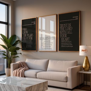 May include: Three framed wall art pieces with gold frames and black backgrounds. The art features inspirational quotes from the Bible. A sofa, coffee table, and lamp are in the room. The text on the art includes "FOR I KNOW THE PLANS I HAVE FOR YOU", "ROMANS 8:28", and "TRUST IN THE LORD WITH ALL YOUR HEART".