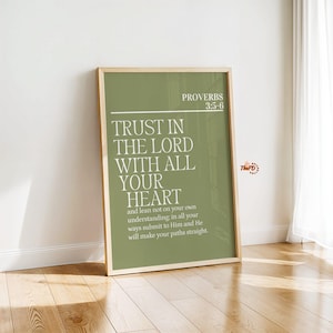 Può includere: Una stampa incorniciata con il testo "TRUST IN THE LORD WITH ALL YOUR HEART" in bianco su sfondo verde. La stampa include anche il testo "PROVERBI 3:5-6" ed è esposta su un pavimento in legno.