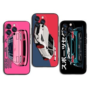 May include: Three phone cases featuring car designs. The first case is pink with a pink car graphic and Japanese text. The second case is red and blue with a white car graphic. The third case is black with a teal car graphic and Japanese text.