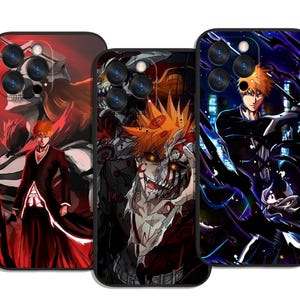 Op de afbeelding: Drie telefoonhoesjes met illustraties in anime-stijl. De hoesjes hebben een zwarte rand en een glanzende afwerking. De ontwerpen tonen een personage met oranje haar in verschillende actieposes, met een donker kleurenpalet.