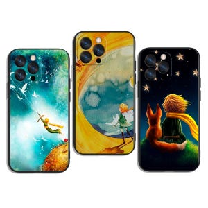 Può includere: Tre custodie per telefono con illustrazioni de "Il Piccolo Principe". Una custodia mostra il principe che vola con gli uccelli, un'altra lo raffigura in una scena ad acquerello e la terza lo mostra con una volpe sotto un cielo stellato. Ogni custodia ha un bordo nero.