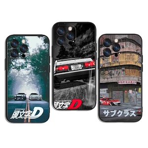 Könnte beinhalten: Drei Handyhüllen mit Auto-Designs. Eine Hülle zeigt eine Straße durch einen Wald mit zwei Autos und japanischem Text. Eine andere zeigt ein Auto, das auf einem schwarz-weißen Hintergrund rast. Die dritte Hülle zeigt ein rotes Auto vor einem Gebäude mit japanischem Text.