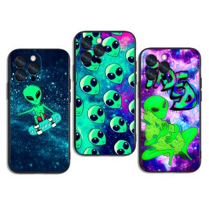 May include: Three phone cases with alien-themed designs. One case features a green alien skateboarding against a starry background. Another has repeating green alien faces on a teal and pink background. The third case displays a green alien with the word "Wasted".