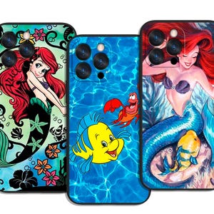 May include: Three phone cases featuring mermaid-themed designs. One case has a mermaid with red hair and a black tail on a green background. Another has a blue water background with Flounder and Sebastian. The third case has a mermaid with red hair and a blue tail.