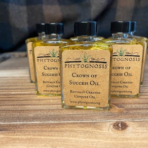 May include: Five small glass bottles with brown paper labels. The labels have the text "PHYTOGNOSIS" and "CROWN OF SUCCESS OIL" printed on them. The bottles contain a clear yellow liquid.