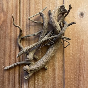 May include: A collection of dried, brown, woody roots with a gnarled and twisted texture. The roots vary in thickness and length, featuring a rough, bark-like surface with small, thin, fibrous tendrils extending from the main stems.