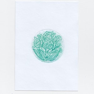 Puede incluir: Ilustración floral de color turquesa sobre una tarjeta rectangular blanca. La obra de arte presenta un diseño circular de flores y hojas estilizadas. El dibujo está centrado en la tarjeta, con el color turquesa contrastando con el fondo blanco.