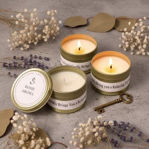 May include: Three lit candles in gold tins with the text "Aromatic Candle Brings You a Relaxing Experience". One tin is open, displaying the text "HOME AROMA". A decorative key and dried flowers are also present.