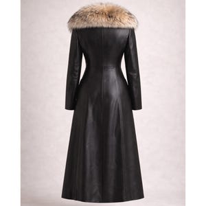 May include: A long, black leather coat with a fur collar. The coat has a fitted silhouette and a flared skirt. The fur collar is a mix of brown, tan, and cream colors. The coat is a classic style.