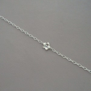 May include: A silver chain bracelet with a delicate flower charm.