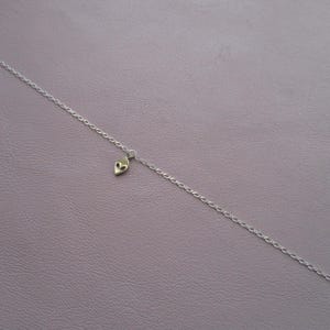 Puede incluir: Un collar de cadena de plata con un peque&ntilde;o dije de extraterrestre.
