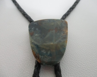 May include: A bolo tie with a dark gray and brown stone pendant. The stone has a marbled pattern with shades of blue, green, and brown.