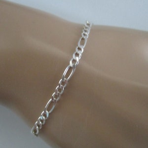 May include: A silver chain bracelet with a figaro link pattern.