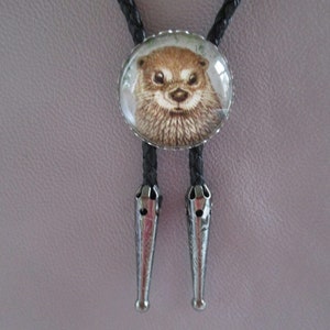 May include: A black bolo tie with a round glass pendant featuring a close-up image of an otter's face.