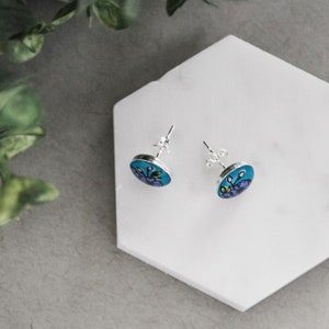 Peut inclure: Une paire de boucles d'oreilles en argent avec un motif floral bleu et violet.