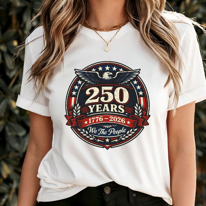 Peut inclure: T-shirt blanc avec un motif circulaire comm&eacute;morant 250 ans, de 1776 &agrave; 2026. Le motif pr&eacute;sente un aigle, des &eacute;toiles et le texte "250 YEARS" et "We The People" dans un code couleur patriotique rouge, blanc et bleu.