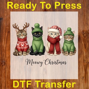 May include: A DTF transfer featuring four cartoon cats dressed for Christmas. The cats wear sweaters, hats, and scarves in festive colors. Text includes "Ready To Press" and "Meowy Christmas".
