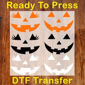 May include: Ready To Press DTF Transfer sheet featuring four different jack-o'-lantern face designs. The designs include orange, black, and white faces with triangle noses and various mouth shapes. The text "Ready To Press" and "DTF Transfer" are in yellow.