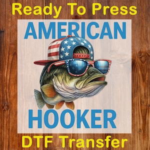 May include: DTF transfer featuring a bass wearing sunglasses and a hat with an American flag design. The words "Ready To Press", "AMERICAN", "HOOKER", and "DTF Transfer" are displayed in the image.