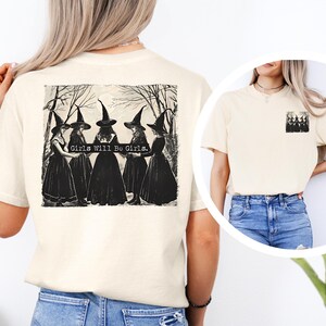Puede incluir: Camiseta color crema con un gr&aacute;fico en blanco y negro de cinco figuras con atuendo de bruja, con el texto "Girls Will Be Girls". Una versi&oacute;n m&aacute;s peque&ntilde;a del gr&aacute;fico est&aacute; en el bolsillo.