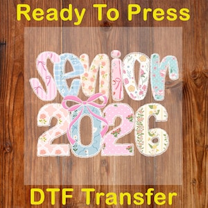 May include: A DTF (Direct to Film) transfer with the words "Senior 2026" in a patchwork design. The text is in pastel colors with floral and bow accents. The words "Ready To Press" and "DTF Transfer" are also visible.