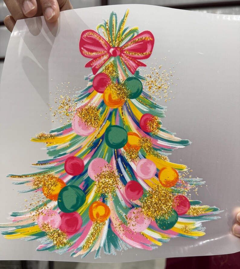 Op de afbeelding: Een kleurrijk kerstboomontwerp met een rode strik. De boom heeft penseelstreken van roze, geel, groen en blauw, versierd met ronde ballen in verschillende kleuren en gouden glitteraccenten. Een feestelijk vakantiethema.