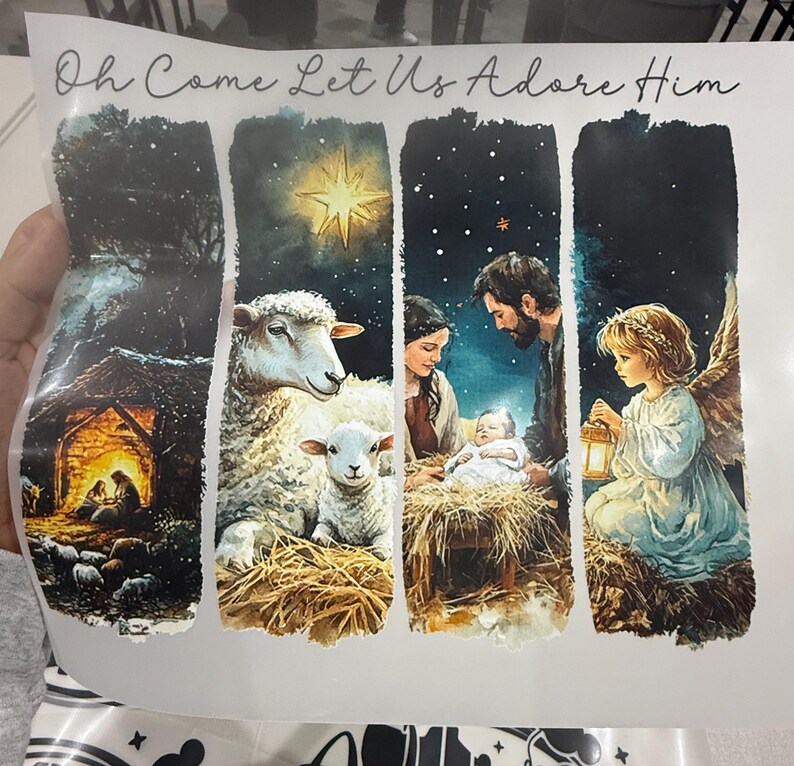 Może przedstawiać: Obraz o tematyce religijnej z napisem "Oh Come Let Us Adore Him". Obraz przedstawia sceny Narodzenia, w tym gwiazdę, owce, Świętą Rodzinę i anioła z latarnią. Grafika jest w stylu akwarelowym.