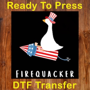 May include: A white goose wearing a patriotic hat, riding a red, white, and blue firework rocket against a black background. The text "Ready To Press" and "FIREQUACKER DTF Transfer" are displayed.