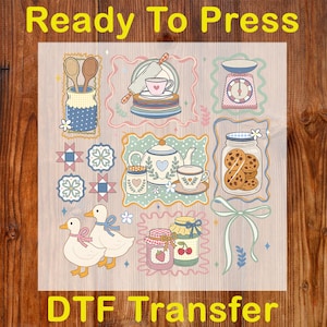 May include: A DTF transfer sheet with various kitchen-themed illustrations. Designs include a teapot, cookies in a jar, ducks, and jars of jam. The words "Ready To Press" and "DTF Transfer" are printed in yellow.