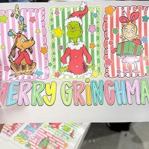 Op de afbeelding: Een kleurrijke afbeelding met drie kerstpersonages: een hond met geweien, de Grinch en een meisje met een cadeau. De tekst "MERRY GRINCHMAS" staat in grote, veelkleurige letters onder de personages.