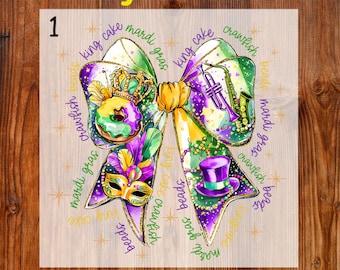 May include: A colorful Mardi Gras-themed DTF transfer design. The design features a bow shape with a king cake, mask, beads, and musical instruments. The words "Ready To Press" and "DTF Transfer" are displayed.