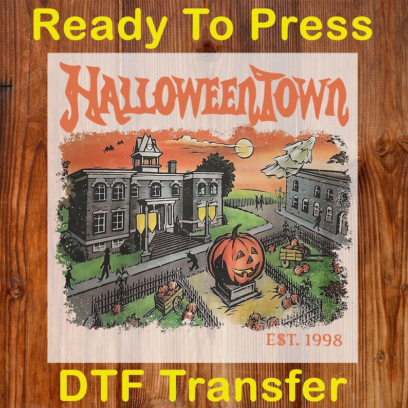 May include: A DTF transfer featuring a Halloween Town design. The design includes a spooky town scene with a jack-o'-lantern, buildings, and the text "HALLOWEENTOWN" and "EST. 1998". The words "Ready To Press" and "DTF Transfer" are also present.