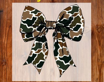 May include: A DTF transfer featuring a large bow with a camouflage pattern in shades of green, brown, and white. The words "Ready To Press" and "DTF Transfer" are in yellow text.