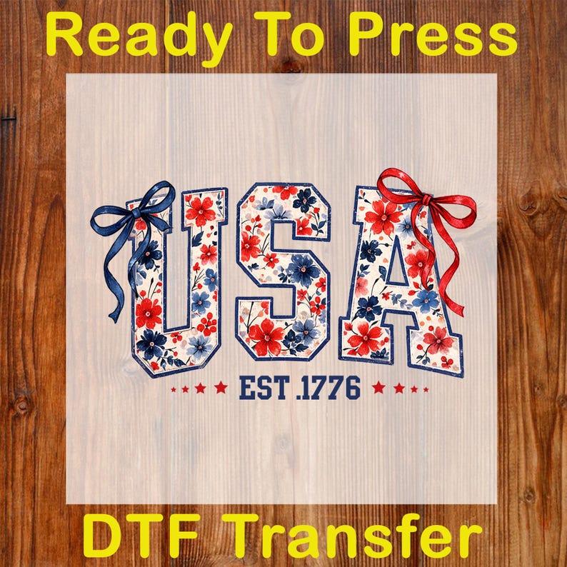 Może przedstawiać: Transfer DTF z napisem "USA" w kwiatowym wzorze z czerwonych, białych i niebieskich kwiat&oacute;w. Litery są obrysowane granatowym kolorem i ozdobione kokardkami. Tekst "EST. 1776" znajduje się pod literami, z gwiazdkami po obu stronach. Obecne są r&oacute;wnież słowa "Ready To Press" i "DTF Transfer".