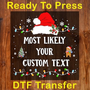 May include: A Christmas-themed DTF transfer design with a Santa hat, string lights, and a teddy bear. The text reads "Ready To Press", "Most Likely Your Custom Text", and "DTF Transfer". The background is a dark brown wood grain.