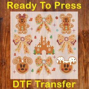 May include: A sheet of DTF transfer designs featuring gingerbread characters, bows, and a castle. The designs are in shades of brown, red, and green, with the text "Ready To Press" and "DTF Transfer" in yellow.