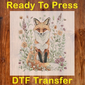 May include: A DTF transfer featuring a detailed illustration of a fox surrounded by wildflowers. The fox has orange and white fur, with black accents. The text "Ready To Press" and "DTF Transfer" are in yellow.